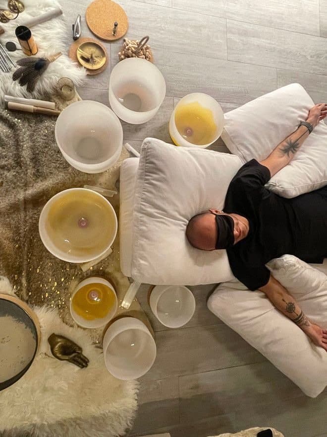 Overhead sound bath setup with a client resting among singing bowls